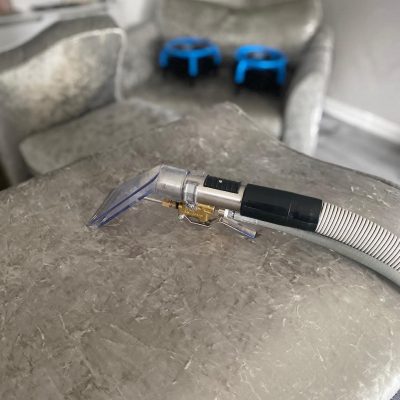 Spot-treating a small stain on a dark rug using a portable extractor, demonstrating precision work for targeted stain removal on delicate fibers.