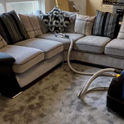 Technician using a specialized handheld upholstery tool to thoroughly clean sof